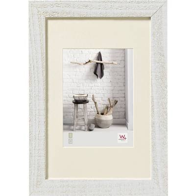 Cadre en bois présentant une image d'un intérieur rustique : tabouret, panier et bol en bois devant un mur de briques blanches.