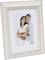 Un couple souriant s'enlace sur une photo de 15 x 20 cm dans un cadre en bois blanc.