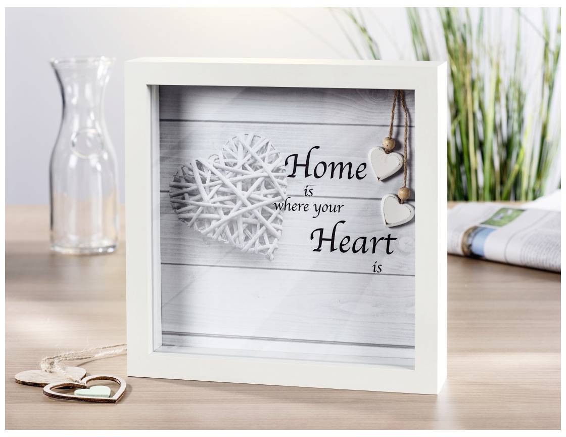 Un cadre présente un texte qui dit 'Home is where your Heart is' avec un cœur en bois blanc décoratif en arrière-plan.