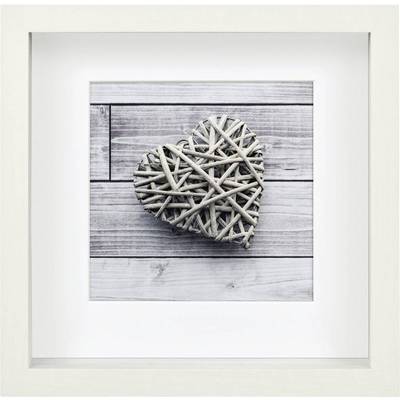 Un cœur tressé de branches repose sur un fond en bois. Décoration simple et naturelle dans un cadre blanc.