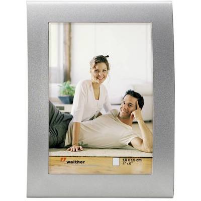 Un homme et une femme sont assis souriants sur le sol dans un cadre photo argenté. Des fenêtres lumineuses sont visibles en arrière-plan.