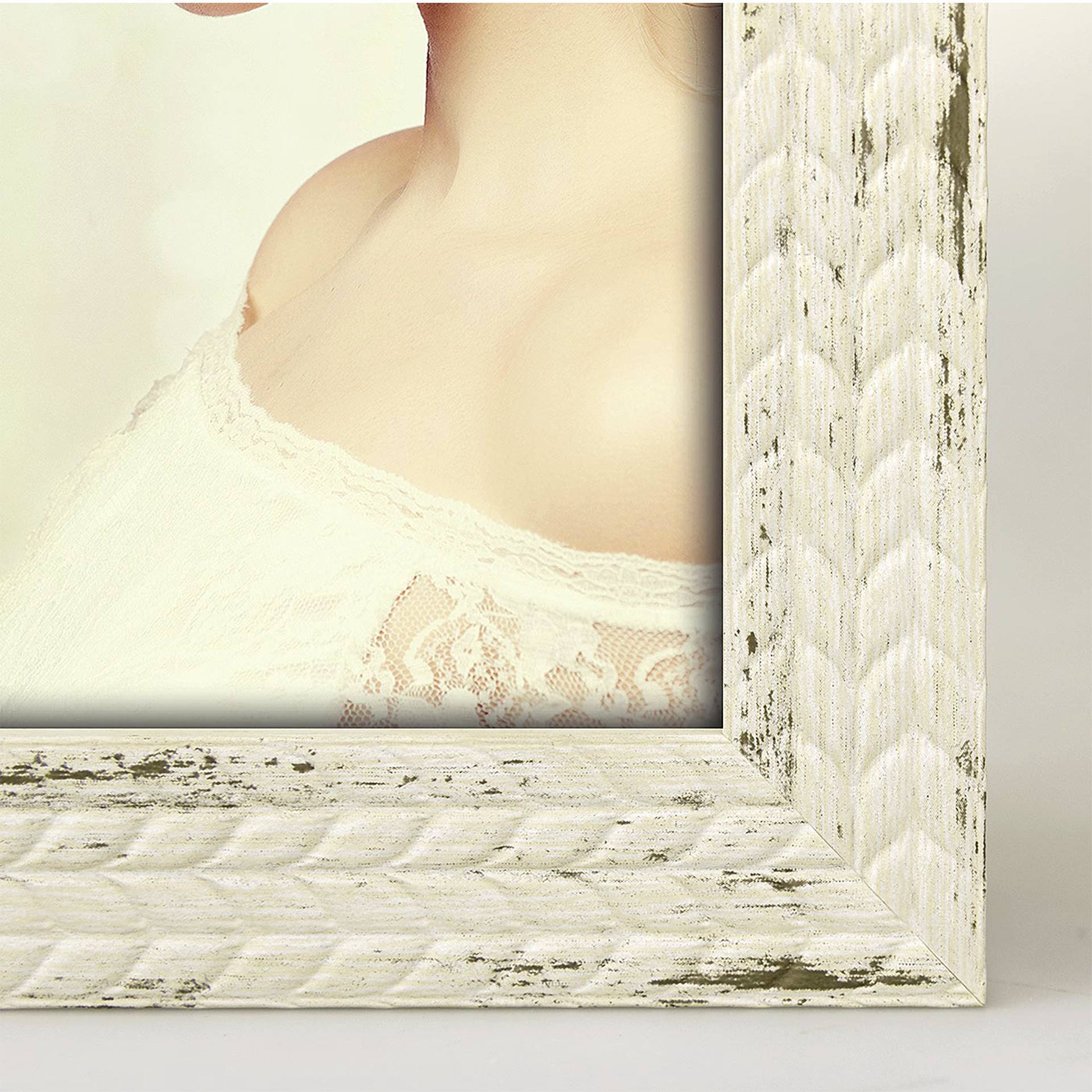 Un cadre en bois vintage contient une photo montrant le haut d'une personne portant une robe blanche en dentelle.