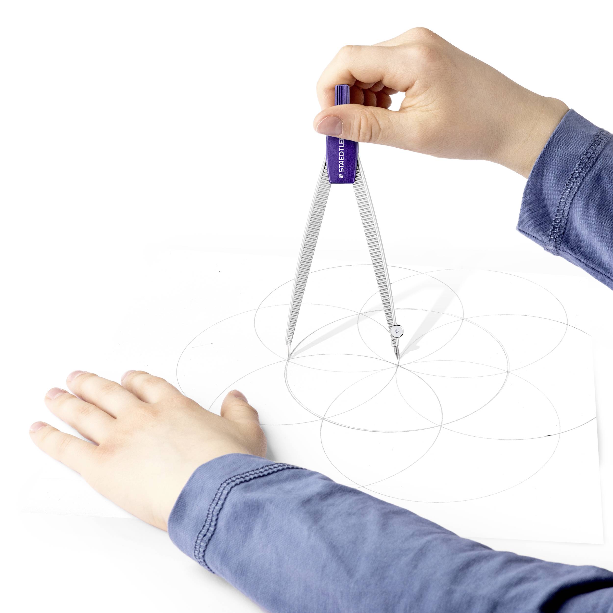 Une personne dessine un motif géométrique sur du papier à l'aide d'un compas. Les mains de la personne tiennent et guident le compas.