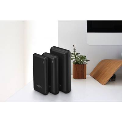 Trois batteries externes noires de différentes tailles sont posées sur une table blanche, à côté d'un écran d'ordinateur et d'une petite plante.
