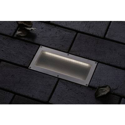 Lampadaire rectangulaire encastré dans un revêtement de sol sombre en pavés, illuminé, avec deux feuilles sèches à proximité.