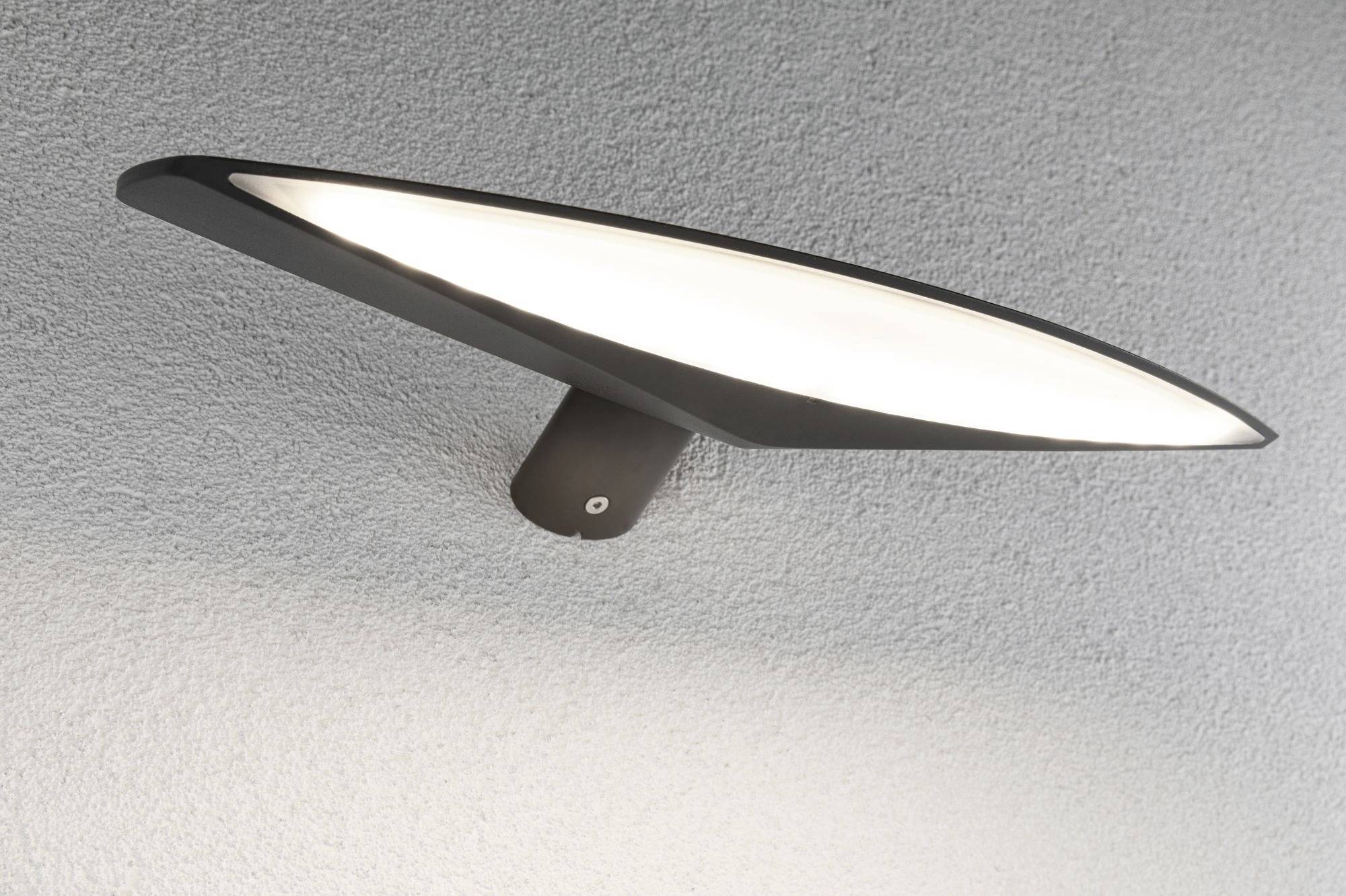 Un luminaire de plafond moderne et plat, à la forme ovale et incurvée, diffuse une lumière douce et blanche sur un plafond gris.