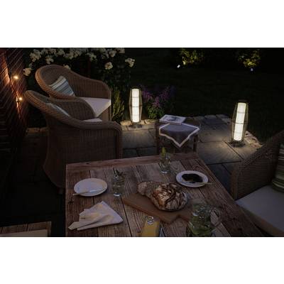 Espace extérieur accueillant avec terrasse en bois le soir, meubles en rotin, éclairage et pain sur la table dans une atmosphère détendue.