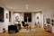 Salon moderne avec un sol en bois, un canapé et un fauteuil, de grandes fenêtres avec des rideaux, des décorations élégantes et un tapis.