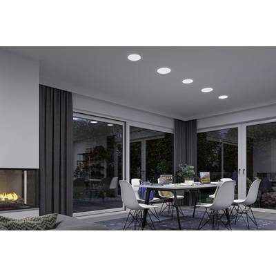 Une salle à manger moderne avec une table et des chaises, de grandes fenêtres donnant sur le jardin et une cheminée au premier plan.