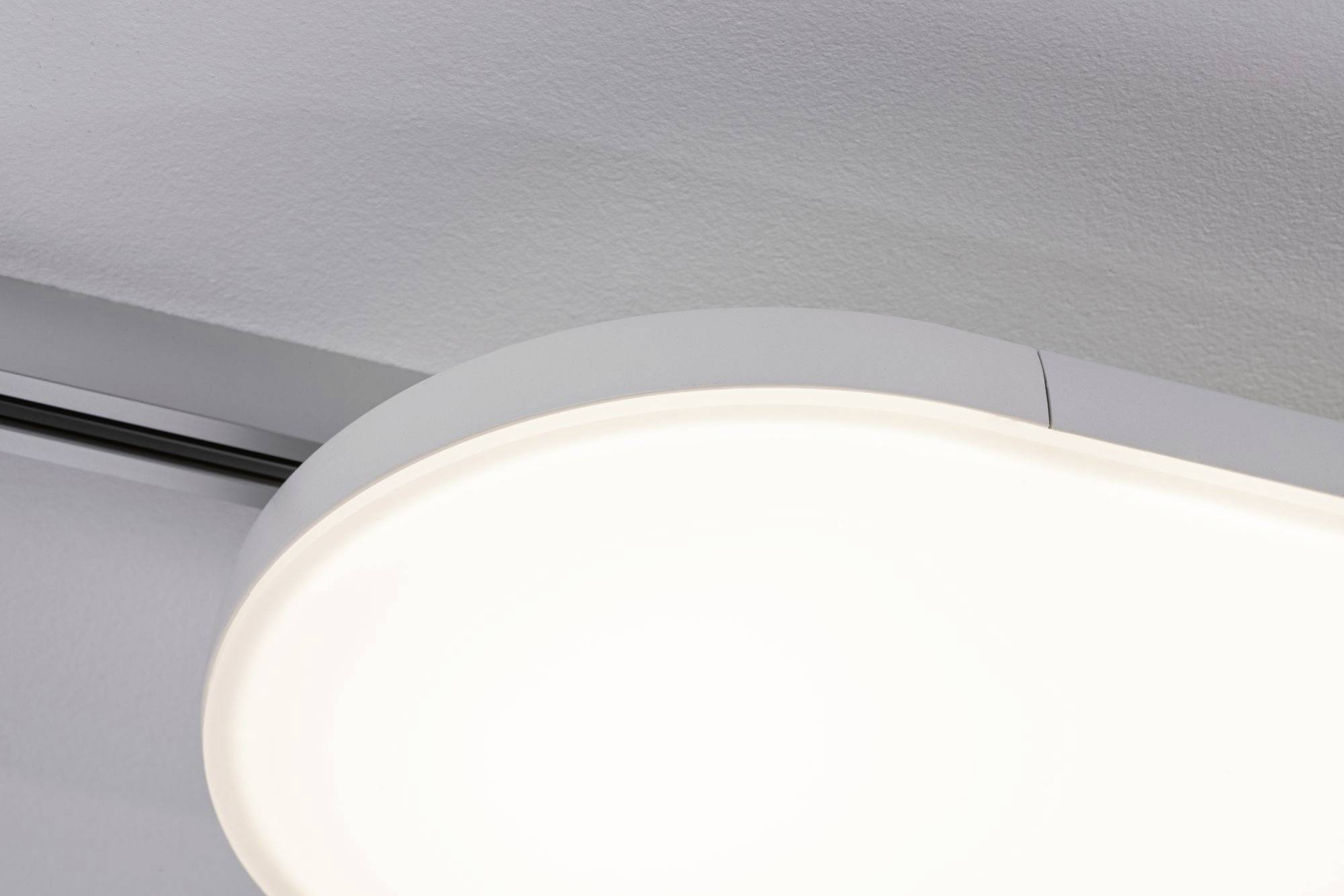 Luminaire plafonnier rond blanc, diffusant une lumière uniforme, fixé à un plafond gris, au design moderne.