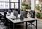Environnement de bureau moderne avec six bureaux, ordinateurs et chaises ergonomiques. La décoration végétale sépare l'espace.