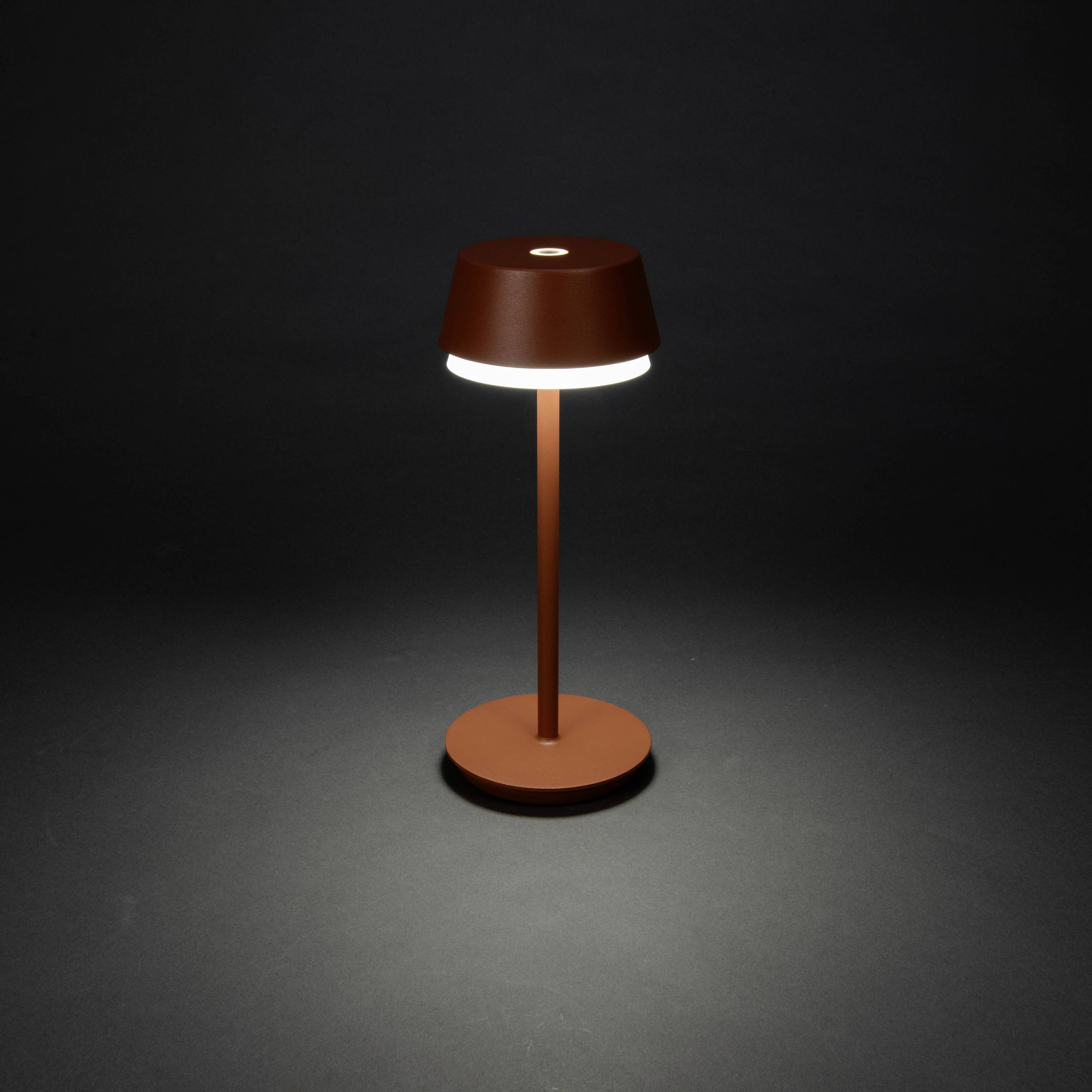 Une lampe de table marron au design moderne s'illumine sur un fond noir.