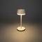 Une lampe de table élégante avec un abat-jour rond illumine une pièce sombre et projette une lueur chaleureuse sur le sol.