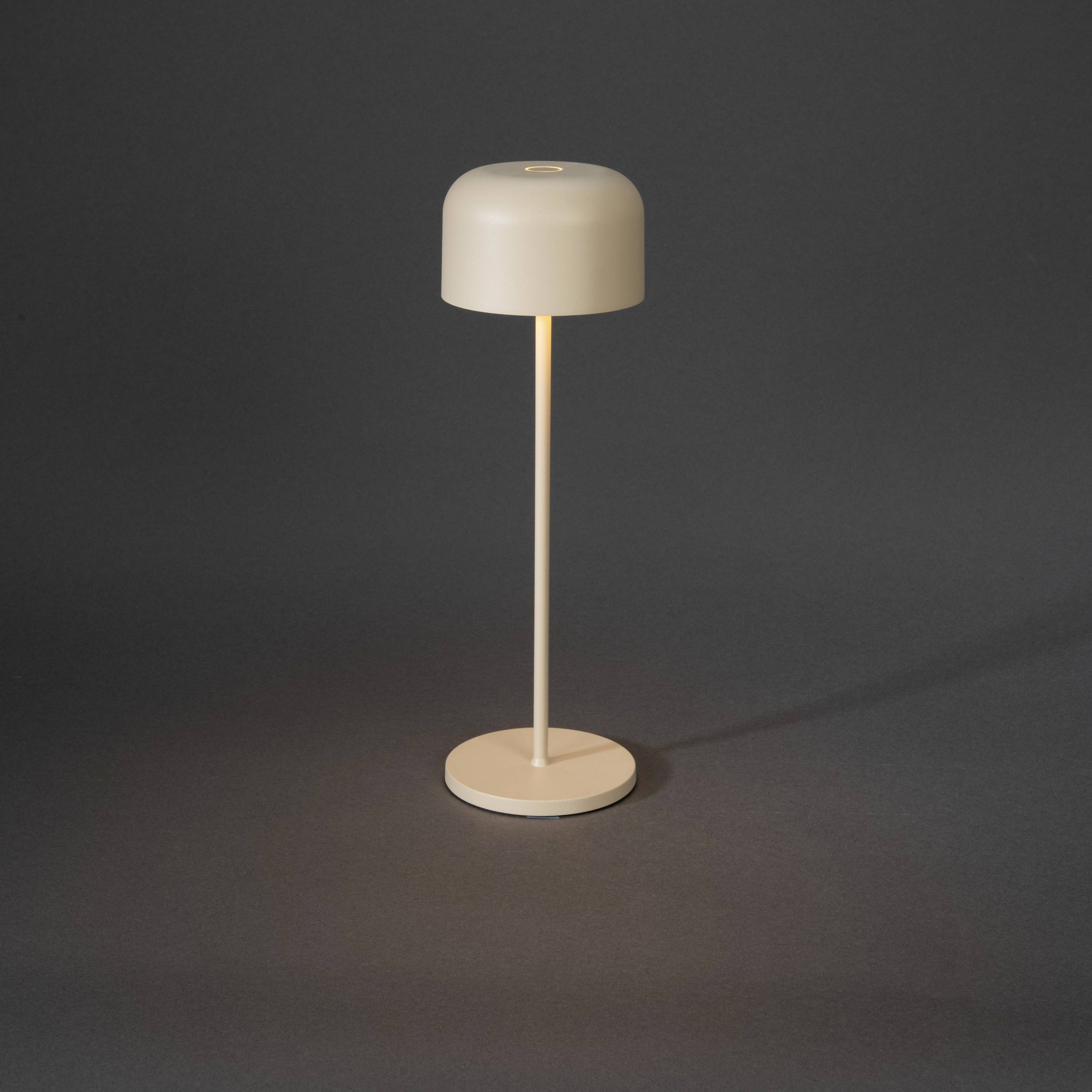Une lampe de table minimaliste avec un abat-jour rond et un pied élancé, posée sur un fond sombre.