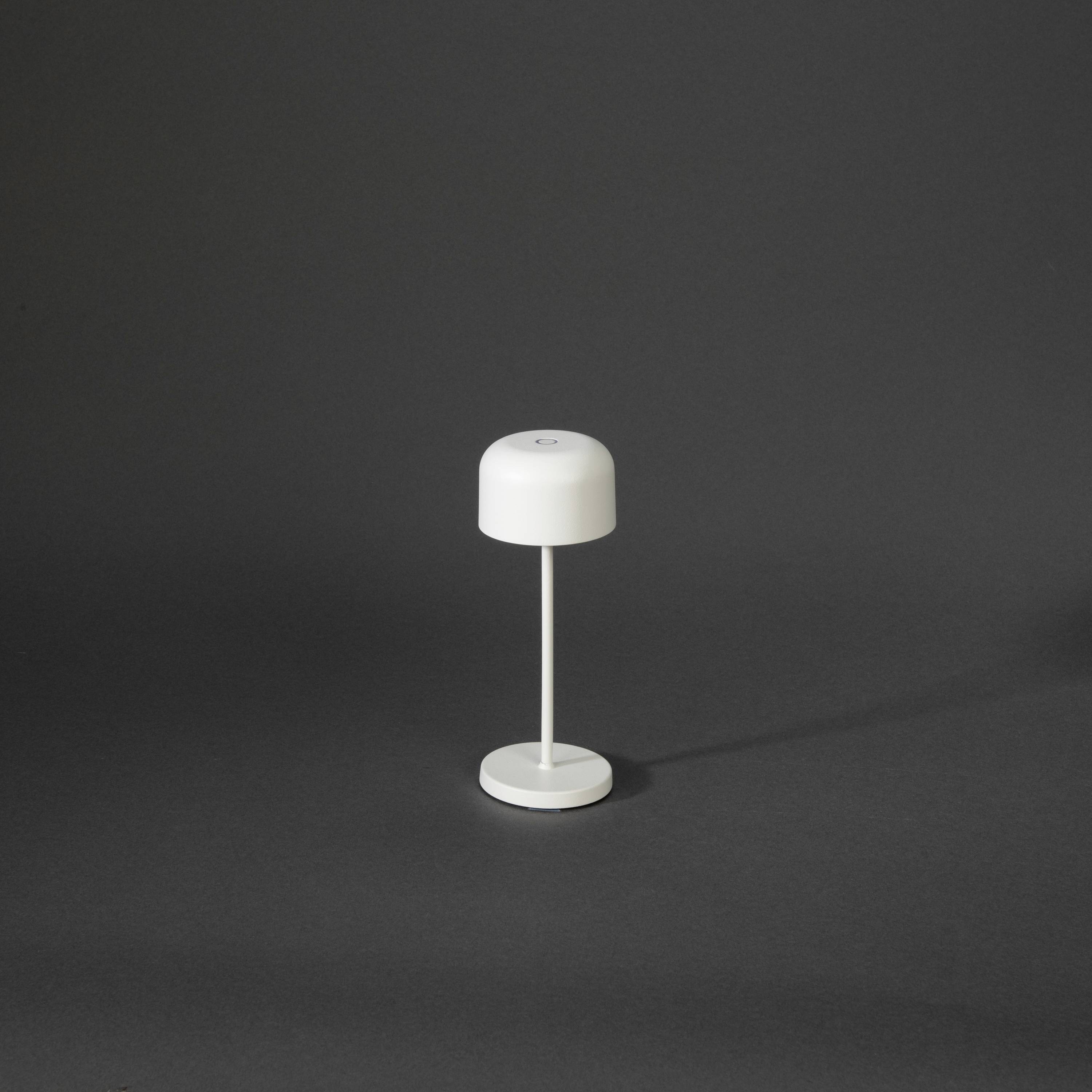 Lampe de table blanche au design moderne sur fond sombre. Abat-jour cylindrique, monté sur un pied élancé.