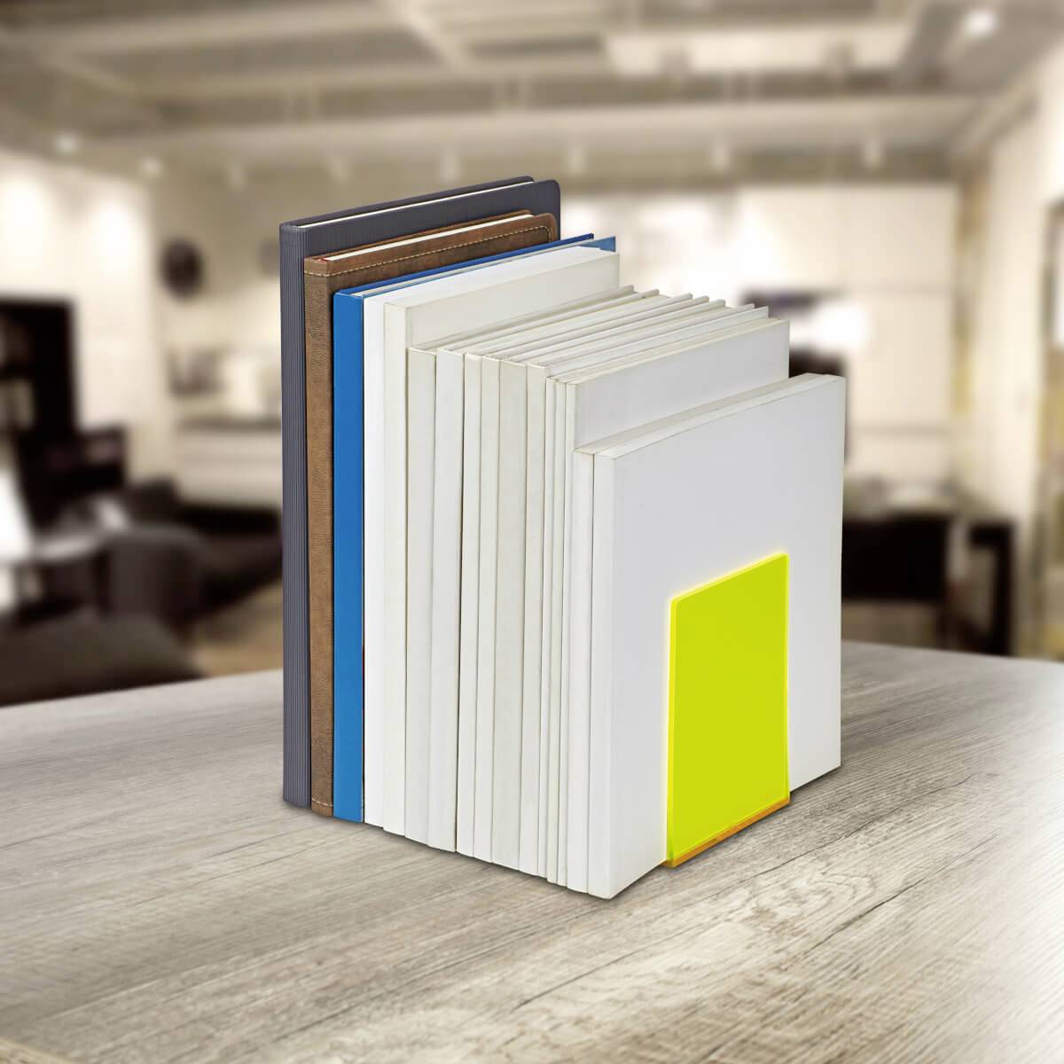 Une rangée de livres est disposée verticalement sur une table dans une pièce lumineuse. L'un des livres a une couverture jaune voyante.