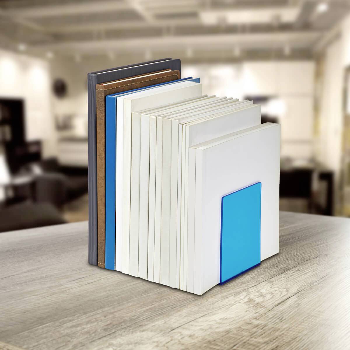 Plusieurs livres, placés côte à côte, sont soutenus par un serre-livres bleu. L'arrière-plan est flou, avec un intérieur moderne reconnaissable.