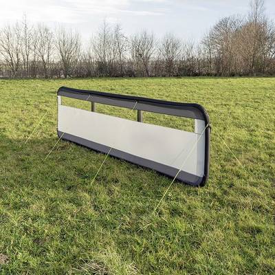 Cage de football portable sur un pré vert, entourée d'arbres dénudés.
