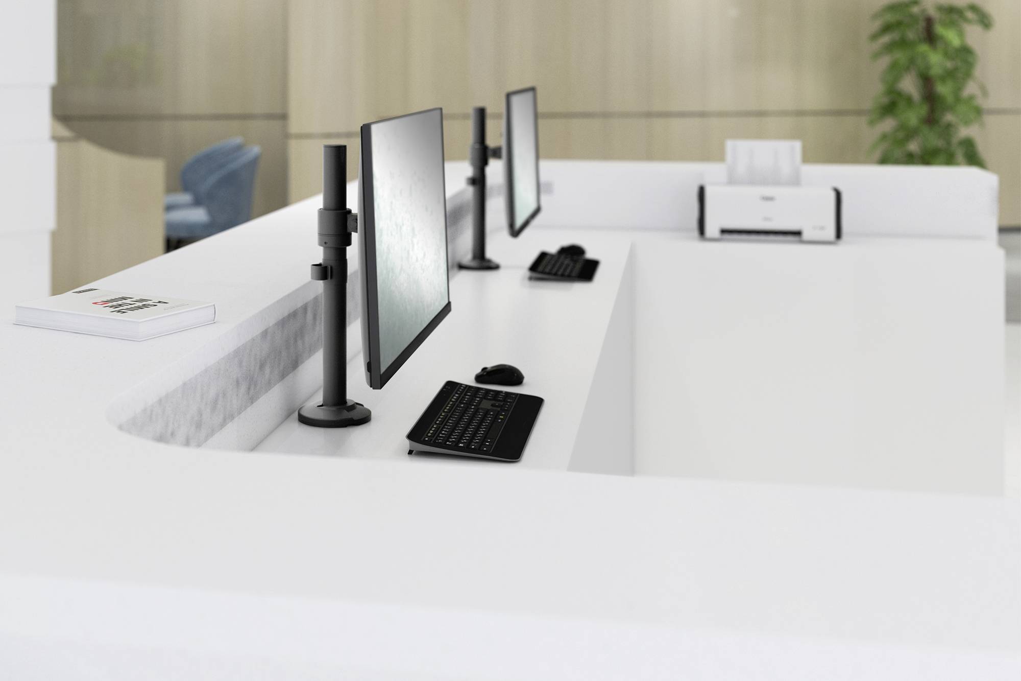 Comptoir d'accueil avec deux ordinateurs, claviers et écrans dans un bureau moderne. Une plante et une imprimante sont visibles en arrière-plan.