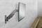 Un écran plat est monté sur un mur gris. L'écran est incliné vers la gauche, à côté d'une surface en bois.