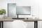 Un bureau moderne et bien rangé avec deux écrans, l'un vertical, l'autre horizontal. Une plante est placée à gauche, et des fournitures de bureau sont disposées à droite.
