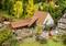 Une mini-ferme avec des maisons à colombages, des cochons dans un enclos et une charrette en bois. Entourée d'arbres et de figurines sur un chemin de gravier.