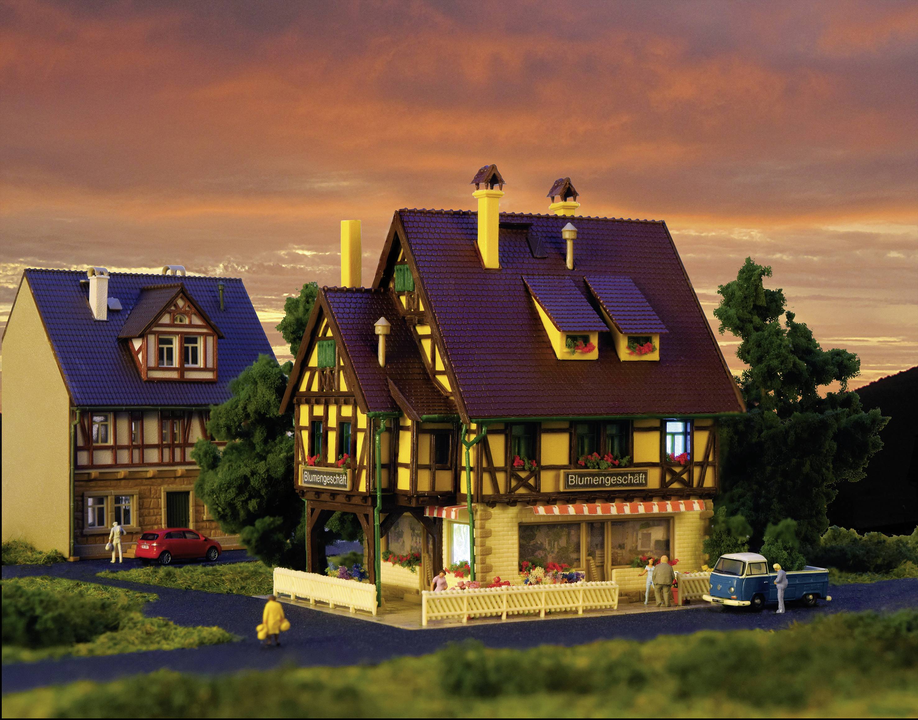 Une maison de poupées de style colombage avec une enseigne 'Fleuriste', entourée de plantes et d'une voiture, devant un ciel orange.