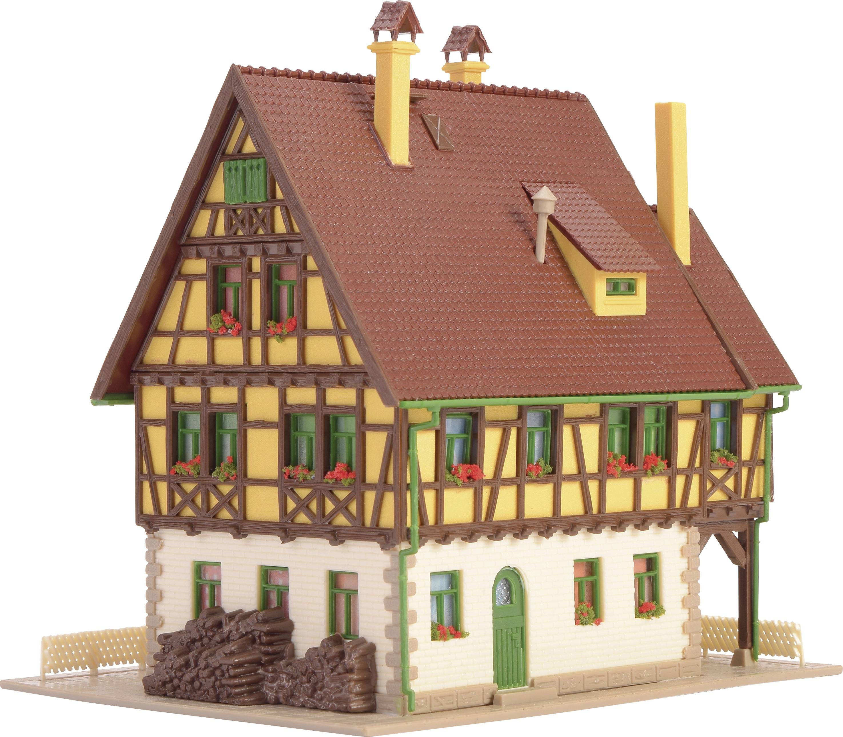 Un modèle d'une maison à colombages traditionnelle avec un toit brun et des volets verts, décoré de pots de fleurs rouges.