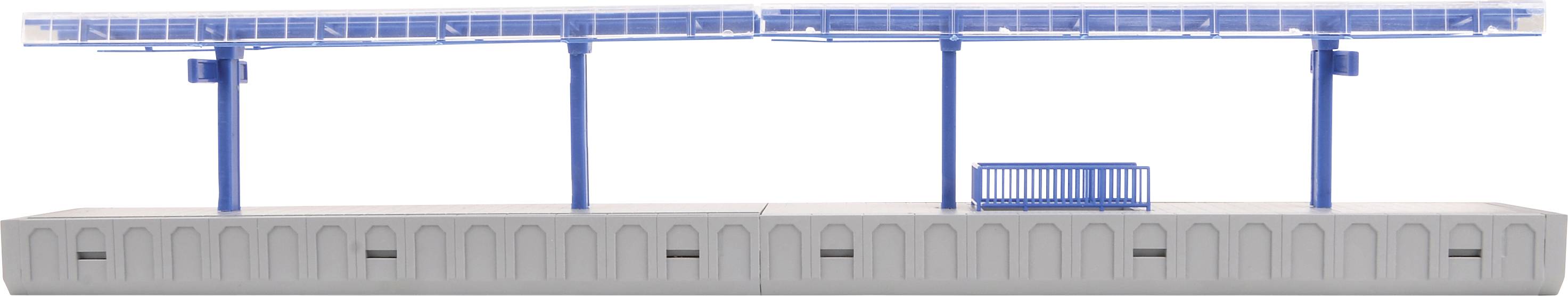 Une gare vide avec un toit bleu et des colonnes bleues. Un banc bleu est installé sur le quai. Un ciel clair en arrière-plan.