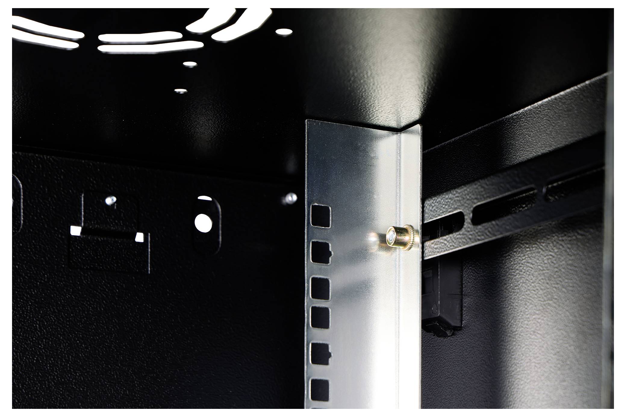 Vue intérieure d'un rack métallique noir avec un support vertical métallique et des panneaux perforés, montrant un point de fixation par boulon.