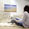 Une personne est assise dans un salon moderne et regarde un grand téléviseur à écran plat sur lequel est affiché une image de plage.