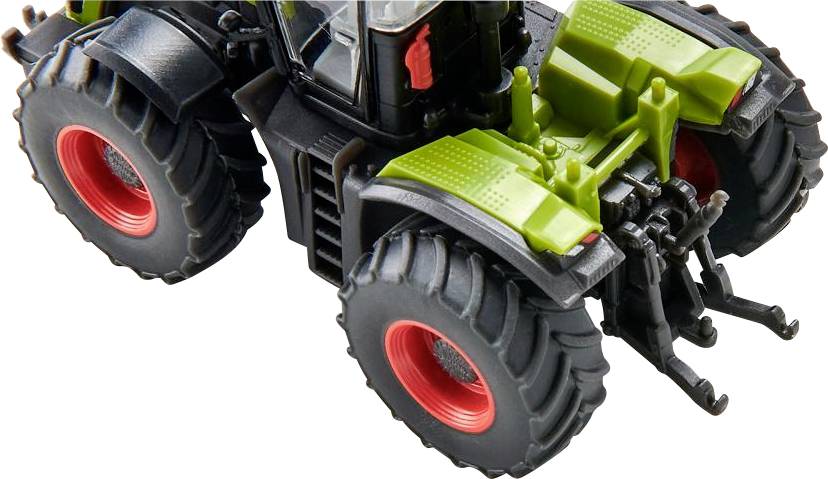 Tracteur-jouet avec de grandes roues noires et des touches vertes, photographié de dessus. Le modèle représente un équipement agricole.