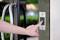 Une main appuie sur un bouton d'un panneau de contrôle d'accès à côté d'une porte vitrée pour ouvrir la porte.