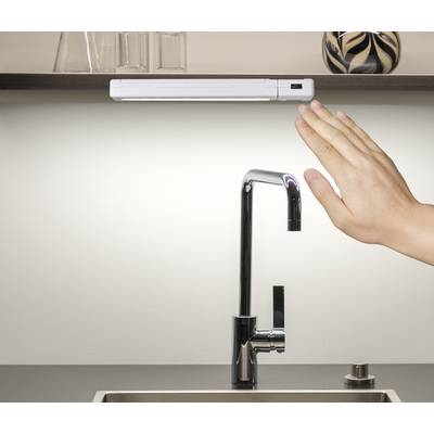 Une main se déplace au-dessus d'un robinet de cuisine moderne, probablement pour activer le robinet sans contact.