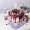 Un grand gâteau décoré avec des baies rouges et de la crème sur une assiette à gâteau bleue. Décoration composée de framboises, de myrtilles, de groseilles et de feuilles de menthe.