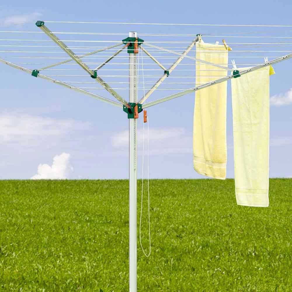 Un parasol de plage sur une prairie verte avec deux serviettes jaunes suspendues, sous un ciel bleu.
