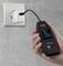 Une main tient un testeur USB branché dans un chargeur connecté à une prise électrique. L'écran affiche différentes valeurs de mesure.