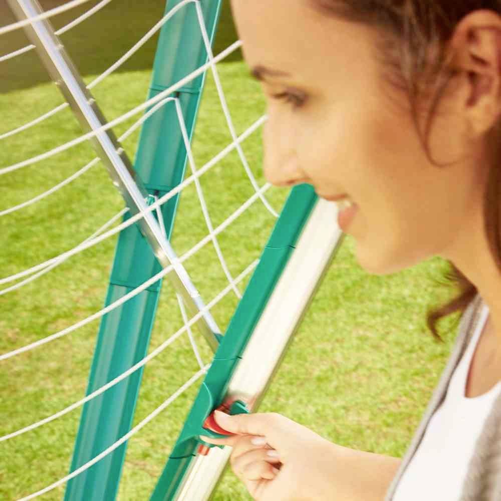 Une femme se tient à côté d'un but de football en extérieur, appuyant sur une protection verte du poteau pour démontrer sa solidité.