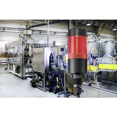 Une ligne de production dans une usine affiche un voyant d'avertissement au premier plan. L'environnement industriel est moderne et bien éclairé.