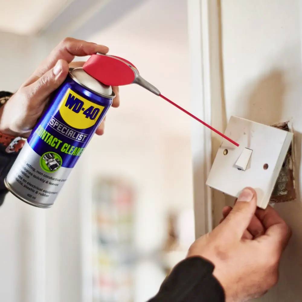 Une personne pulvérise du WD-40 Specialist Contact Cleaner sur un interrupteur pour enlever la saleté.