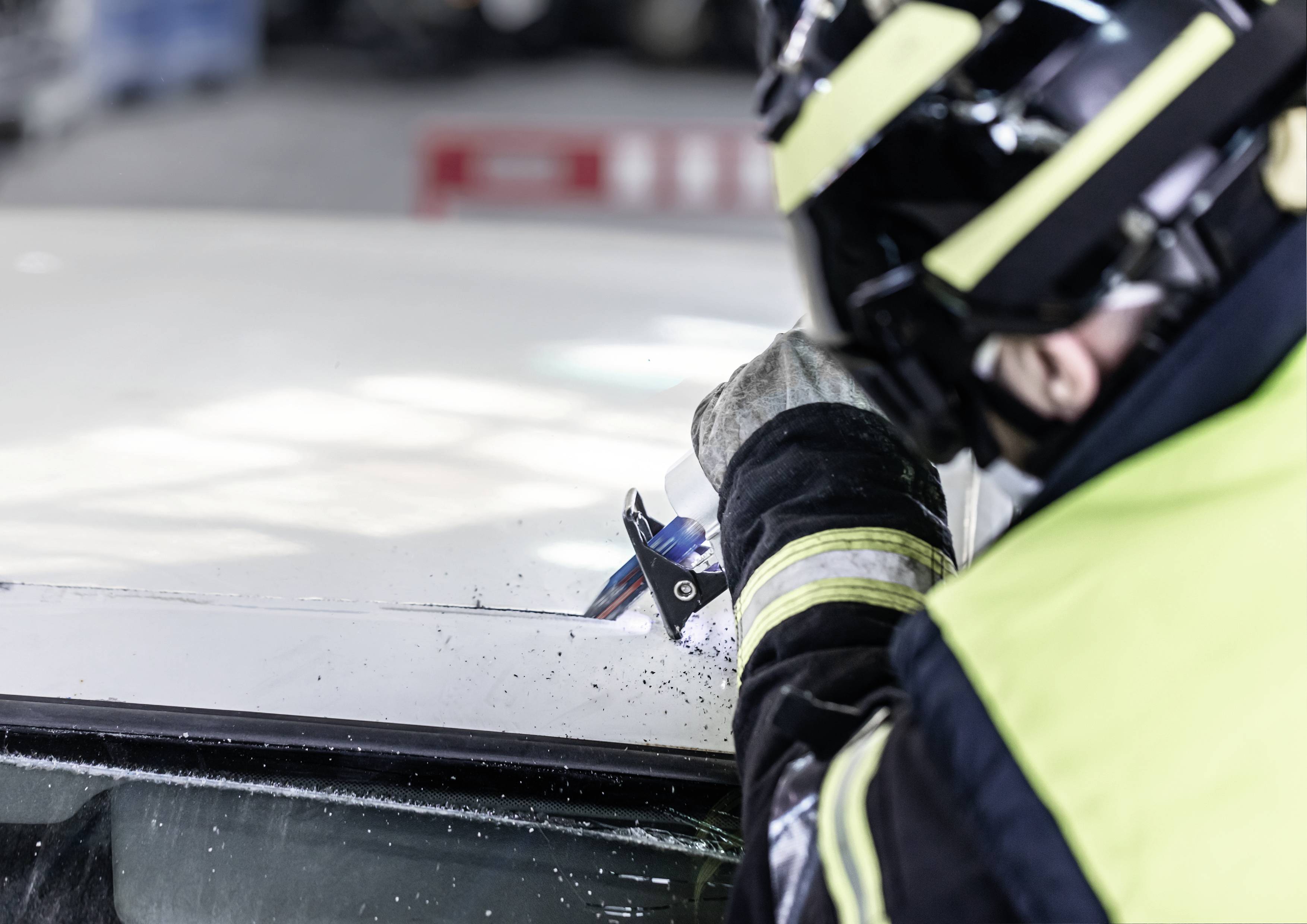 Un pompier coupe le toit d'un véhicule à l'aide d'un ciseau de secours. L'accent est mis sur l'opération de sauvetage.