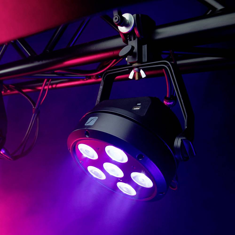 Un projecteur de scène à LED émet une lumière bleue, fixé sur une poutre devant un fond sombre.