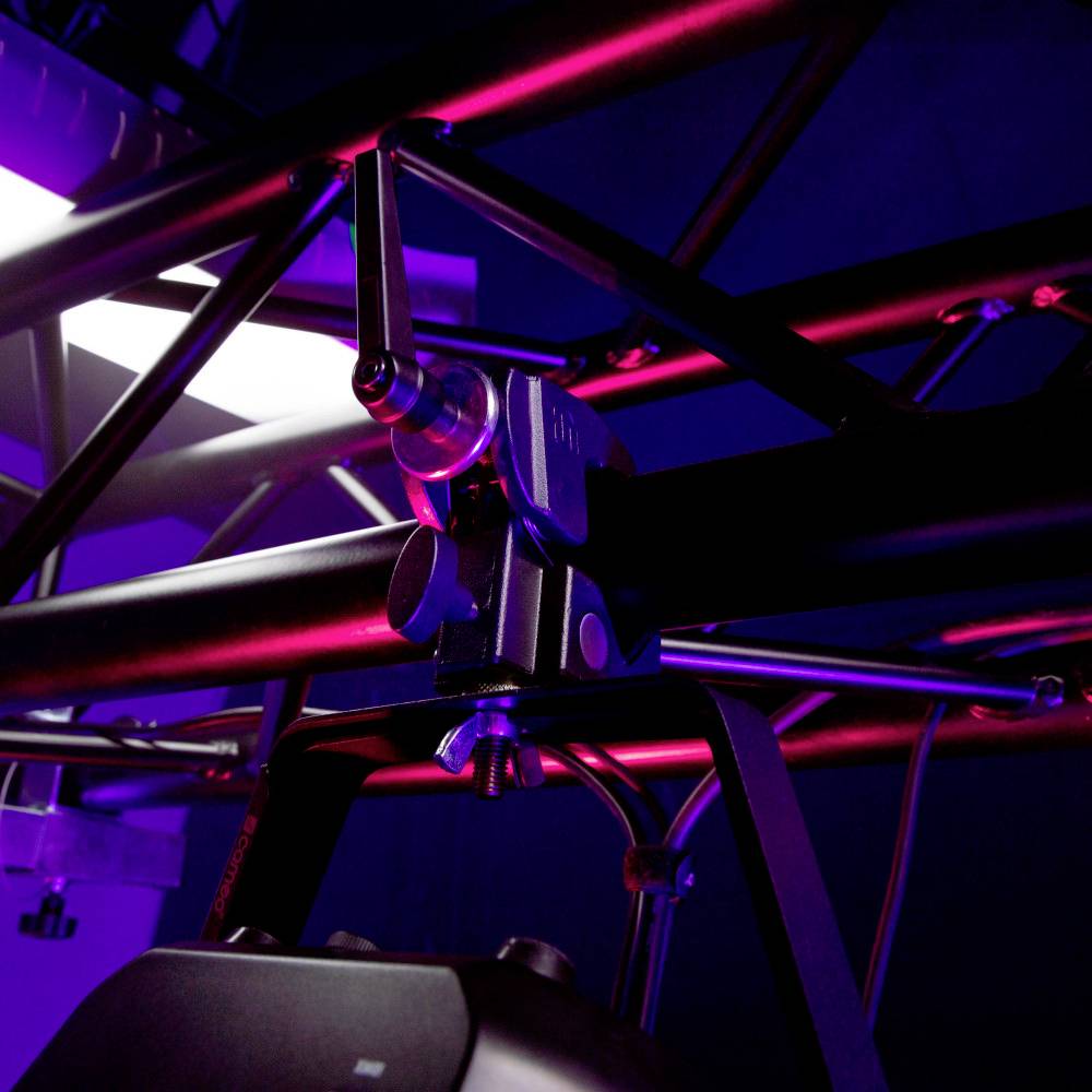 Cadre métallique avec des luminaires et des reflets lumineux dans un espace sombre, soulignant l'équipement technique et l'atmosphère.