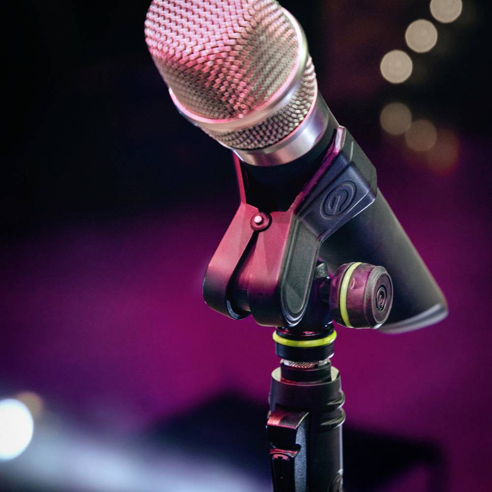 Microphone sur un support devant un arrière-plan flou. Adapté pour le chant ou les enregistrements vocaux lors d'un événement musical.