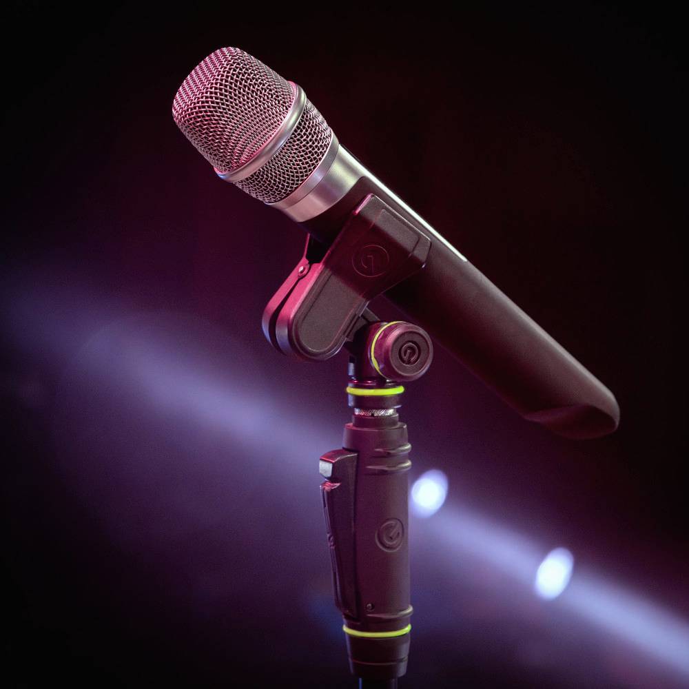 Un microphone sur un support, éclairé par une lumière rouge, symbolise une situation de scène ou d'enregistrement.