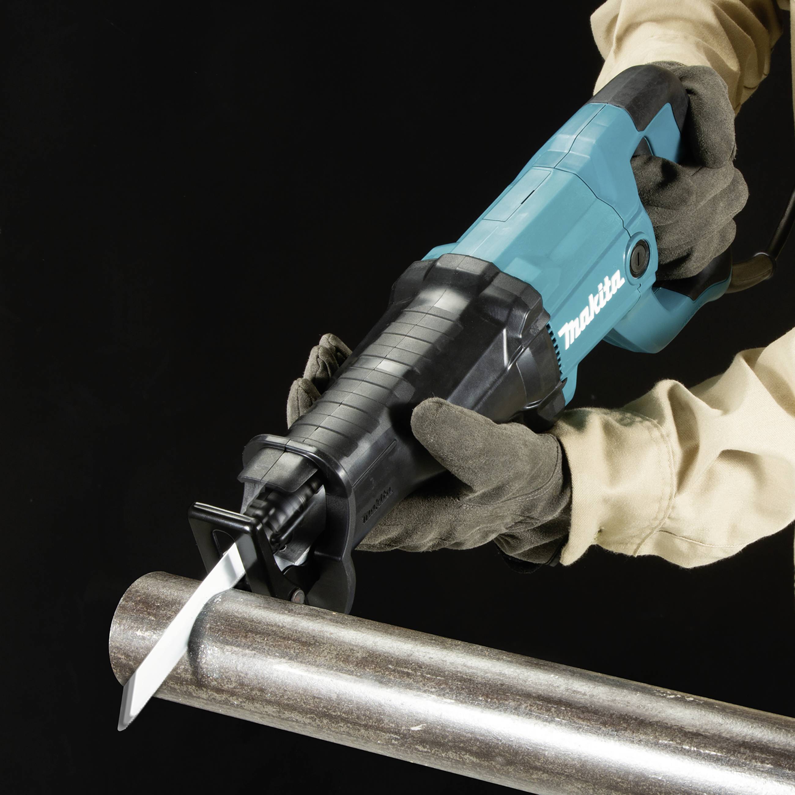 Une personne portant des gants de travail tient une scie électrique prête à être utilisée, suspendue juste au-dessus d'un tuyau métallique en vue de réaliser un travail.