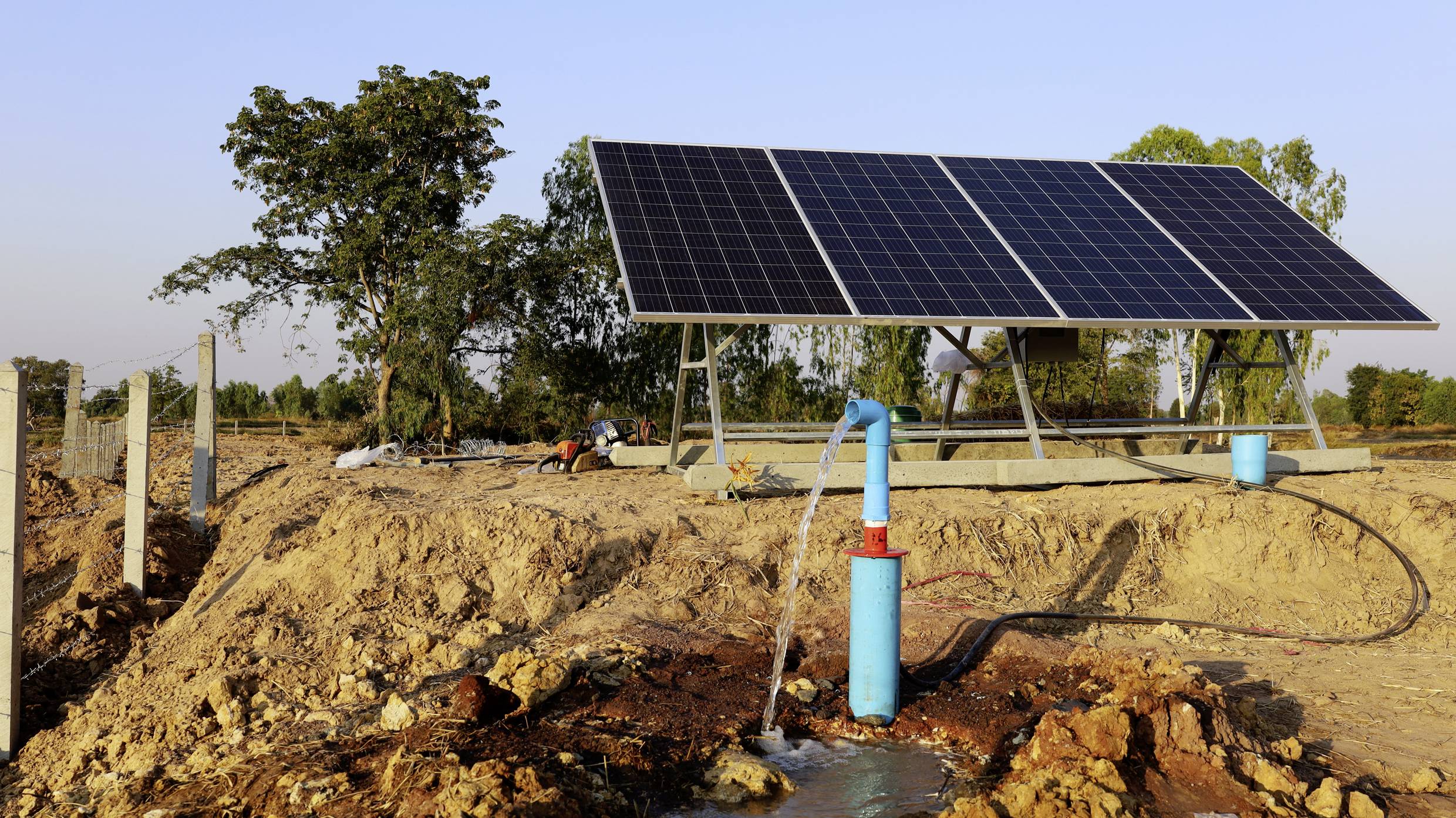 Pompe à eau solaire dans un environnement rural, extrayant de l'eau du sol. Grands panneaux solaires installés en arrière-plan.