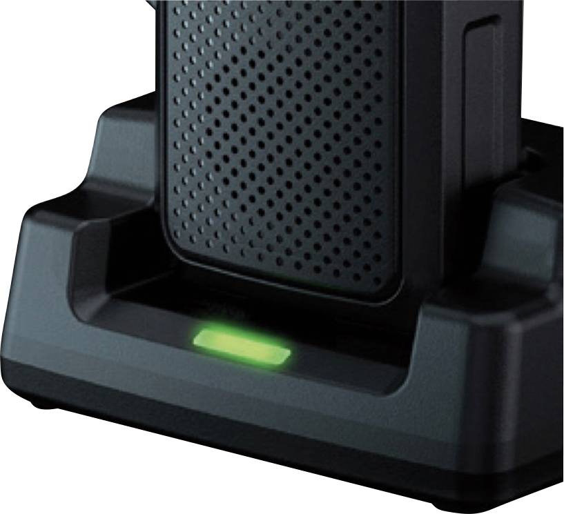 Un talkie-walkie est posé sur sa station de charge, un voyant vert indiquant que l'appareil est en cours de chargement.