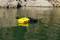 Deux coffres de sécurité flottants, l'un jaune et l'autre noir, dérivant sur un plan d'eau vert, entourés de rochers.