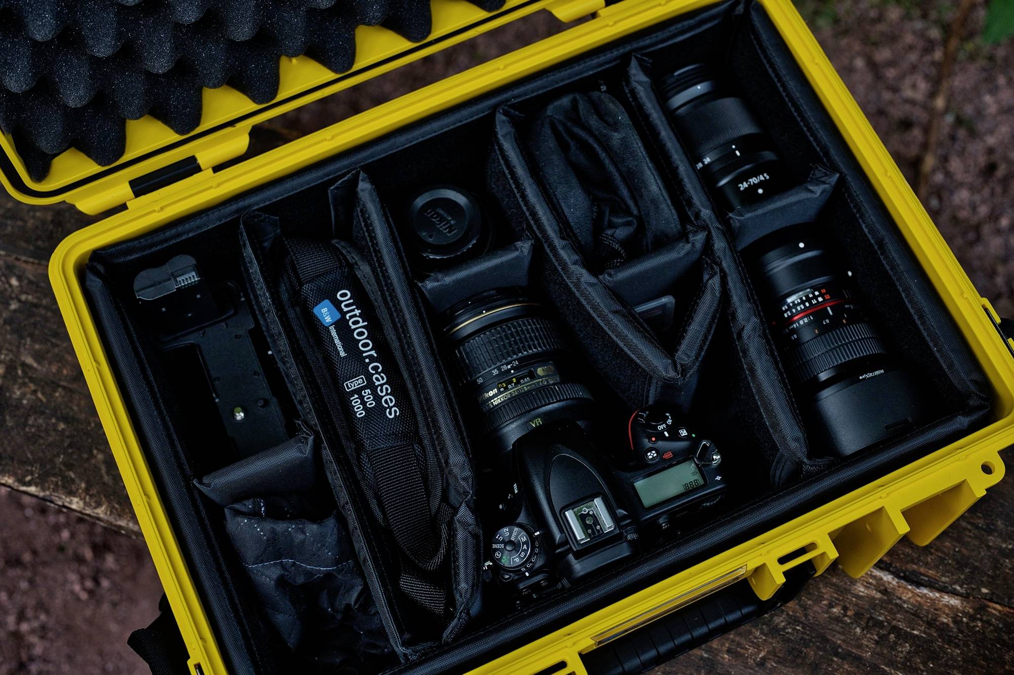 Un sac de caméra jaune contenant plusieurs objectifs, un appareil photo et des accessoires, protégés par des compartiments rembourrés à l'intérieur.